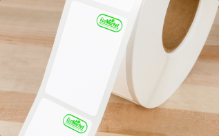 A roll of labels with a strip extending out and each label showing a green brand logo printed in the upper right hand corner