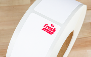 A roll of labels with a red brand logo printed in the upper right hand corner