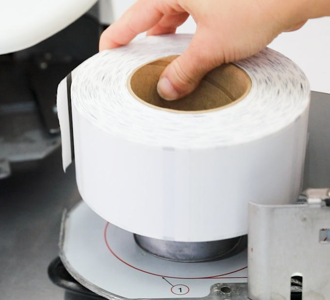 A roll of scale labels being placed into a machine