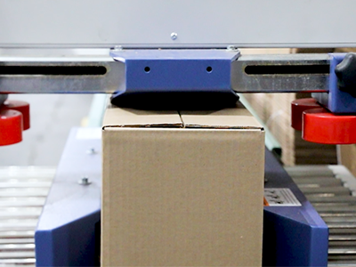 A box being sealed and then rolling down a conveyor before being picked up by a person