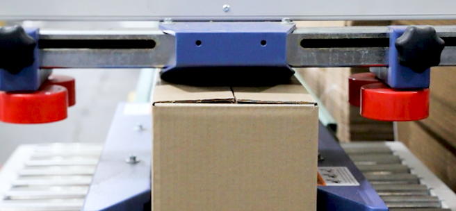 A box being sealed and then rolling down a conveyor before being picked up by a person